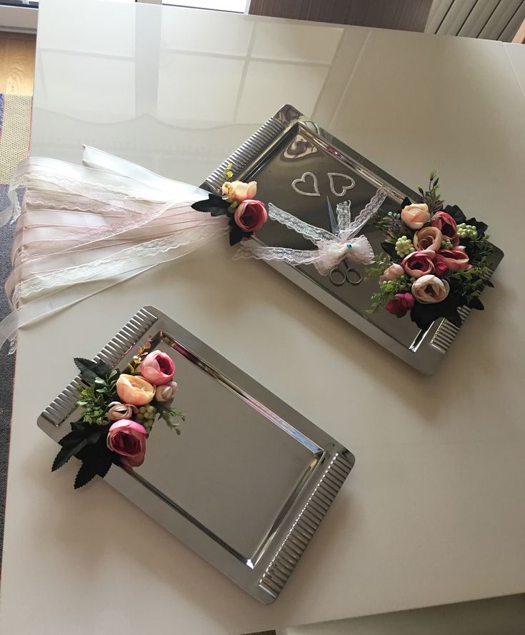 two mirrors decorated with flowers on top of a table