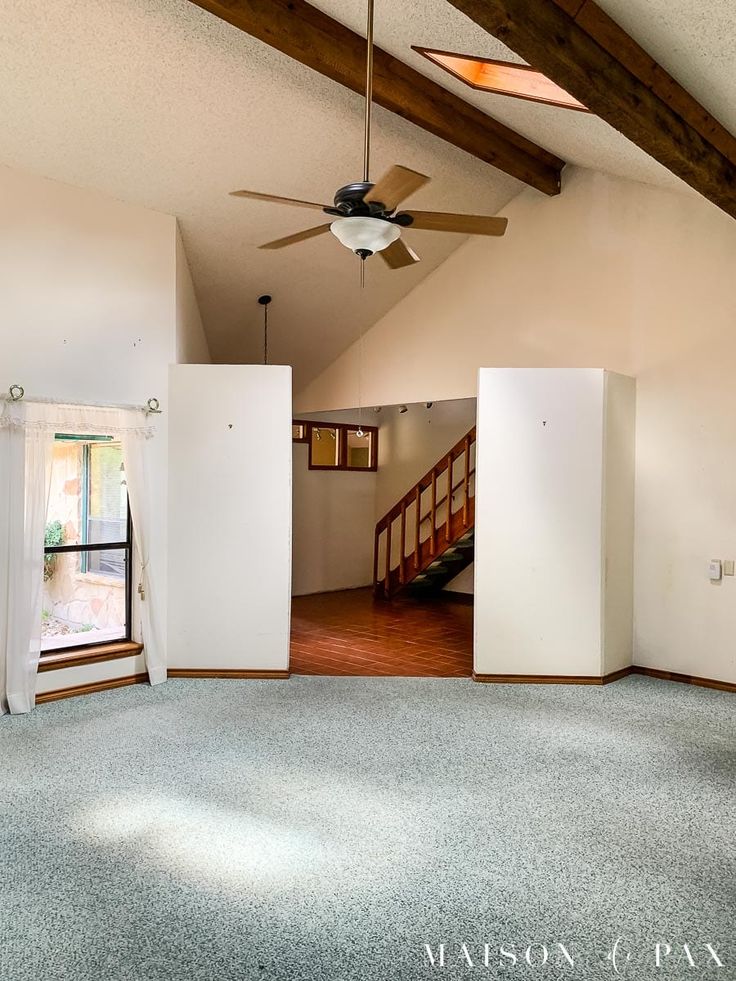 an empty living room with a ceiling fan