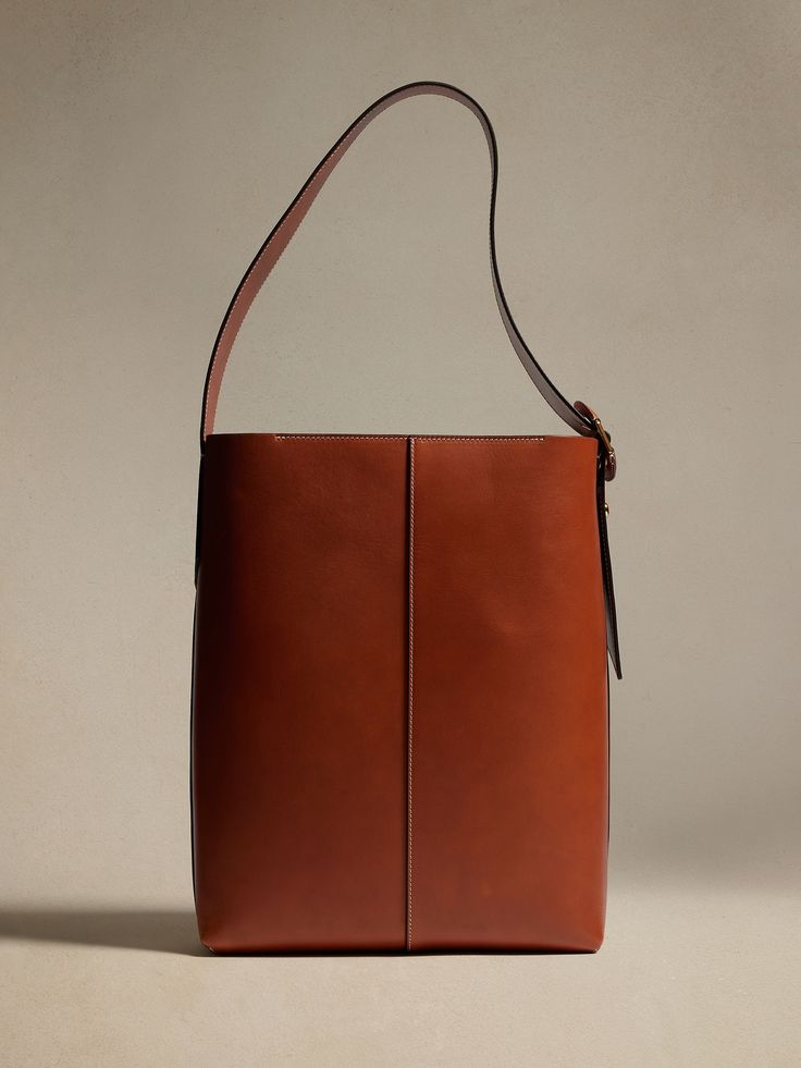 An Italian masterpiece, this sturdy-yet-soft, bonded leather bucket bag uses dark gold signature hardware and contrast stitching to stand above the rest.  Dress it up or down with luxurious ease.  PREMIUM LEATHER: This item is crafted using vegetable Brown Calf Leather Bucket Bag With Gold-tone Hardware, Calf Leather Bucket Bag With Gold-tone Hardware For Workwear, Brown Calf Leather Shoulder Bag With Brass Hardware, Calf Leather Bucket Bag With Leather Handles For Work, Calf Leather Bucket Bag For Work, Brown Calf Leather Bucket Bag, Designer Bucket Bag With Gold-tone Hardware For Work, Modern Bucket Shoulder Bag With Brass Hardware, Rectangular Bucket Bag With Brass Hardware