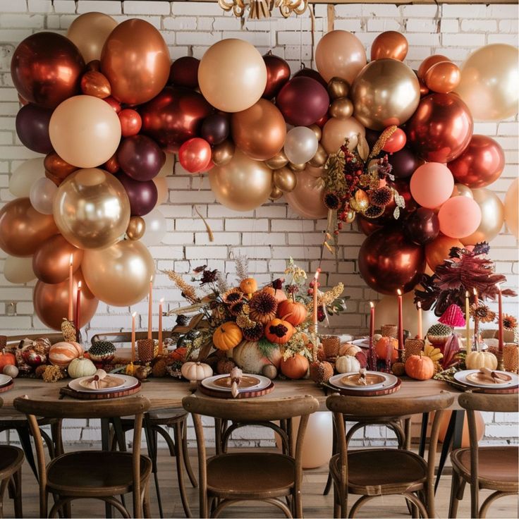 a dining room table is set with fall decorations and balloons hanging from the brick wall