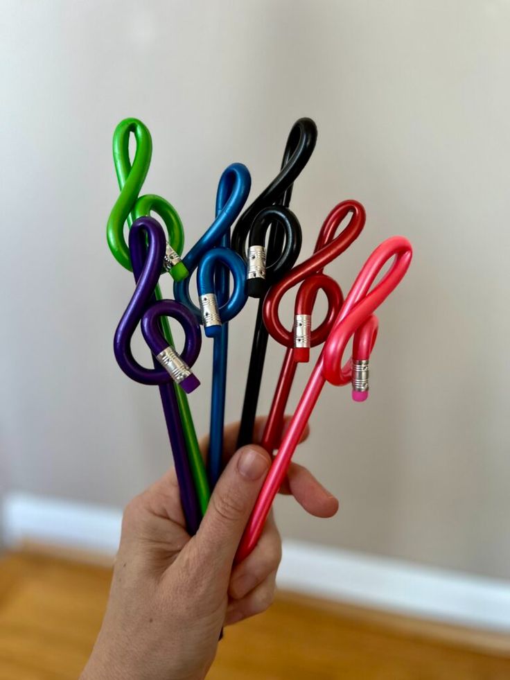 a person holding four different colored scissors in their left hand and the other one has an earphone attached to it