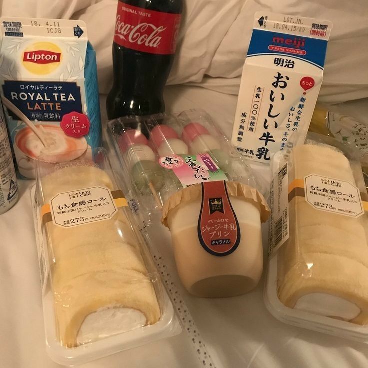 several packaged food items sitting on a bed next to each other in plastic containers and bottles