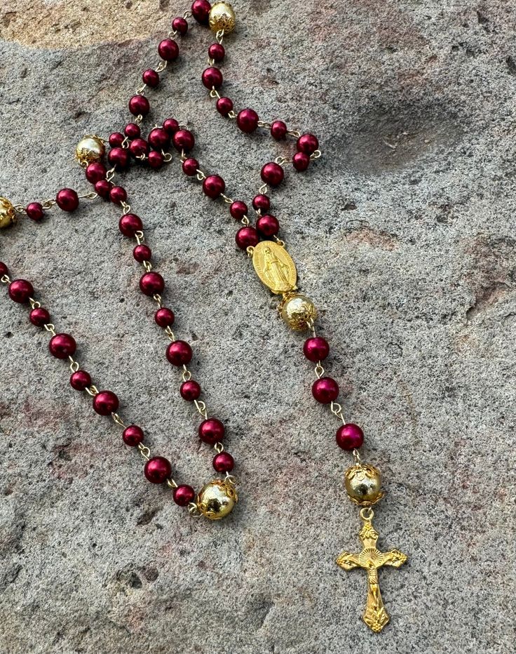 Embrace the sacred union of tradition and beauty with our gold and red rosary, a symbol of unwavering devotion and divine grace. The centerpiece of this divine masterpiece is a radiant gold-tone rosary medallion, intricately designed to symbolize faith, hope, and love, serving as a beacon of spiritual guidance in your daily endeavors. Handcrafted with precision and care, this rosary exudes timeless charm and sophistication, making it the perfect companion for your sacred rituals or a cherished gift for a loved one. Please note, our creations are as unique as you are! Embrace the individuality of your purchase, knowing that colors and beads may vary slightly due to monitor settings and the inherent nature of our artisanal supplies. And remember your satisfaction is our priority please conta Spiritual Gold Rosary With 8mm Beads, Gold Jewelry With 8mm Beads For Blessing, Gold Rosary With Round Beads As Gift, Gold Round Beads Rosary As Gift, Gold Necklaces With 8mm Beads For Blessing, Spiritual Red Crucifix Rosary, Yellow Gold Rosary With Round Beads, Spiritual Yellow Gold Rosary With Round Beads, Gold Spiritual Rosary With Round Beads