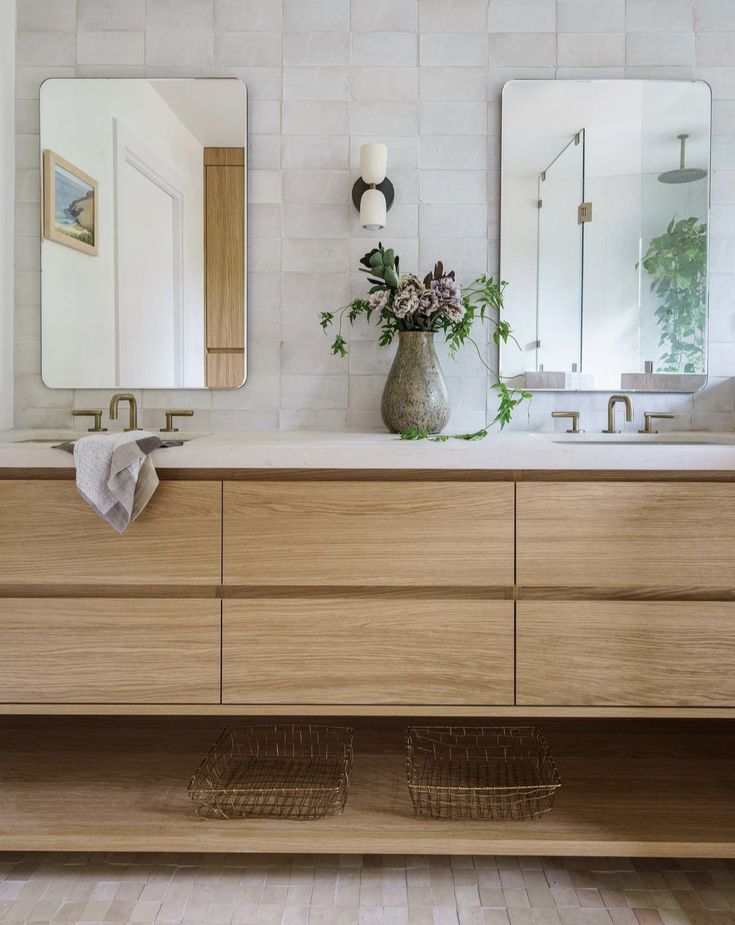 a bathroom with two sinks and mirrors in the wall above it is tiled flooring