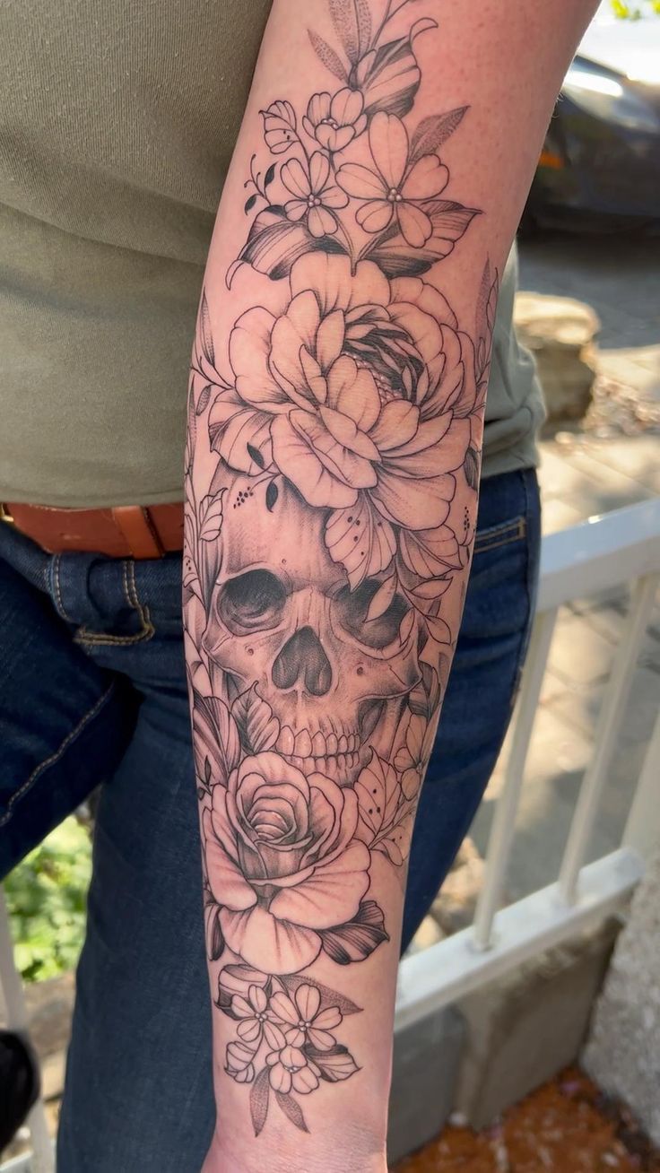 a woman's arm with a skull and flowers on it