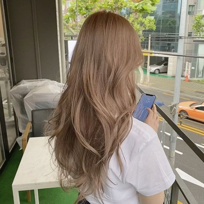 a woman with long hair is looking at her cell phone while sitting on a balcony