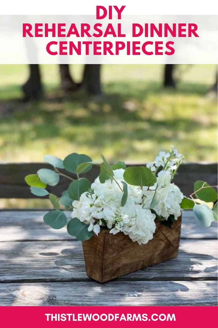 a wooden box filled with white flowers and greenery on top of a picnic table