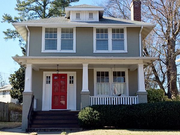 a gray house with white trim and red front door, two women standing in front of it