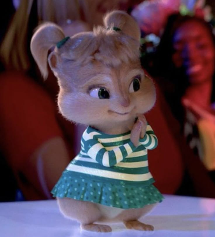 a small toy mouse wearing a green and white striped shirt with polka dots on it's chest