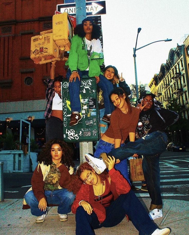 a group of people sitting on top of a street sign next to eachother