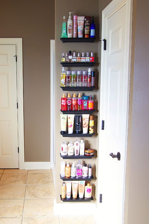 an open door leading into a bathroom with shelves filled with personal care products on the wall