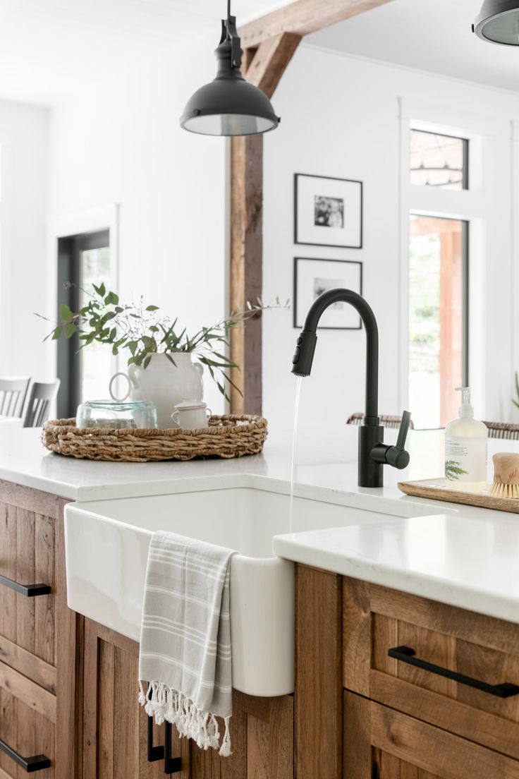 a kitchen with wooden cabinets, white counter tops and hanging lights over the sink area