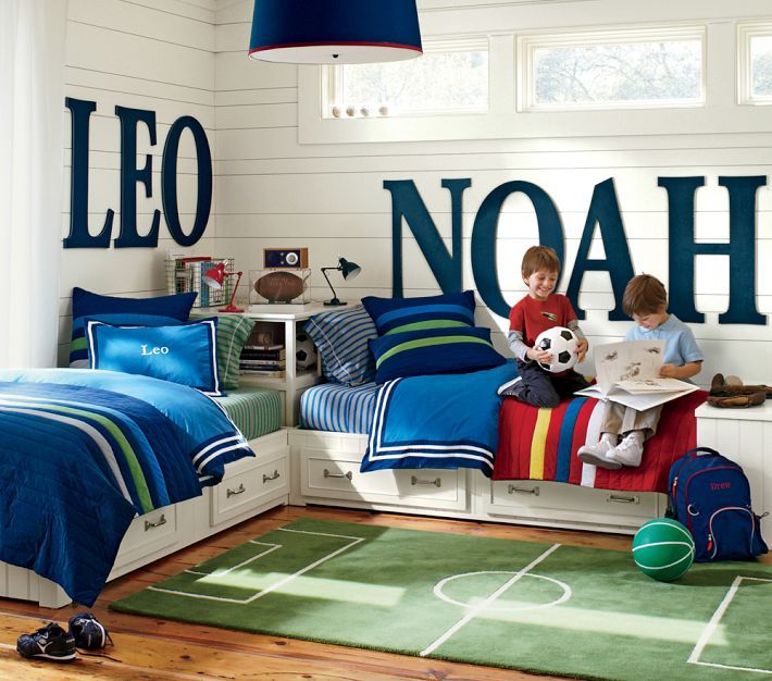 a child's bedroom with blue and white bedding, soccer themed wallpaper