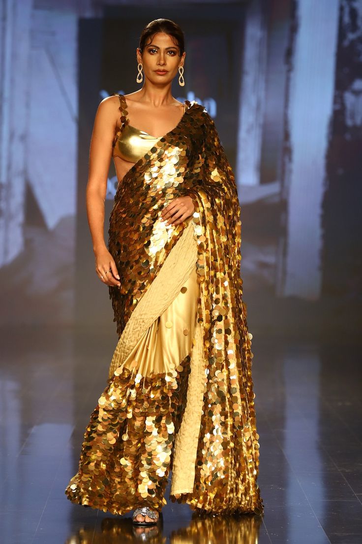 Gold saree with all-over sequin embroidery. Comes with sleeveless blouse and petticoat.
Component: 3
Pattern: Embroidery
Type Of Work: Sequin
Neckline: Sweetheart
Sleeve Type: Sleeveless
Fabric: Foil Georgette
Color: Gold
Other Details: 
Shoulder straps with sequin embroidery
Occasion: Wedding - Aza Fashions Glamorous Festive Pre-draped Saree For Celebration, Bollywood Style Festive Pre-draped Saree With Sequins, Diwali Sequined Pre-draped Saree, Sequin Pre-draped Chinon Saree, Bollywood Style Pre-draped Saree With Sequins, Glamorous Sequined Pre-draped Saree For Festivals, Traditional Pre-draped Art Silk Saree With Sequins, Party Wear Pre-draped Sequined Saree For Festivals, Sequin Chinon Pre-draped Saree For Diwali