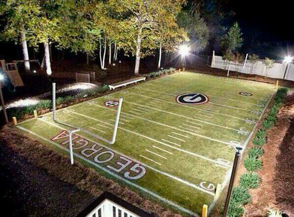 an illuminated football field in the middle of a yard at night with lights on it