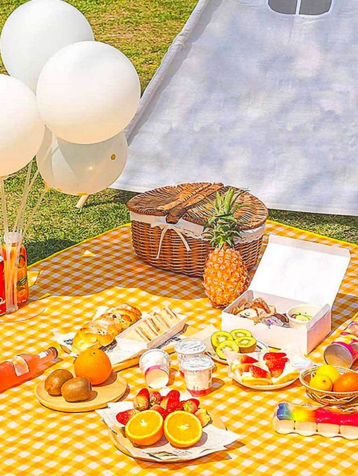 a picnic table with food and balloons on it