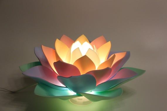 a lit up lotus flower sitting on top of a green table next to a white wall