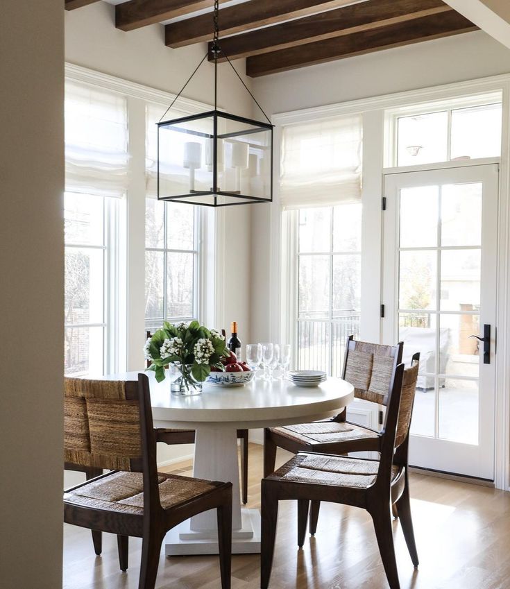 a dining room table with four chairs and a wine bottle on the table in front of it