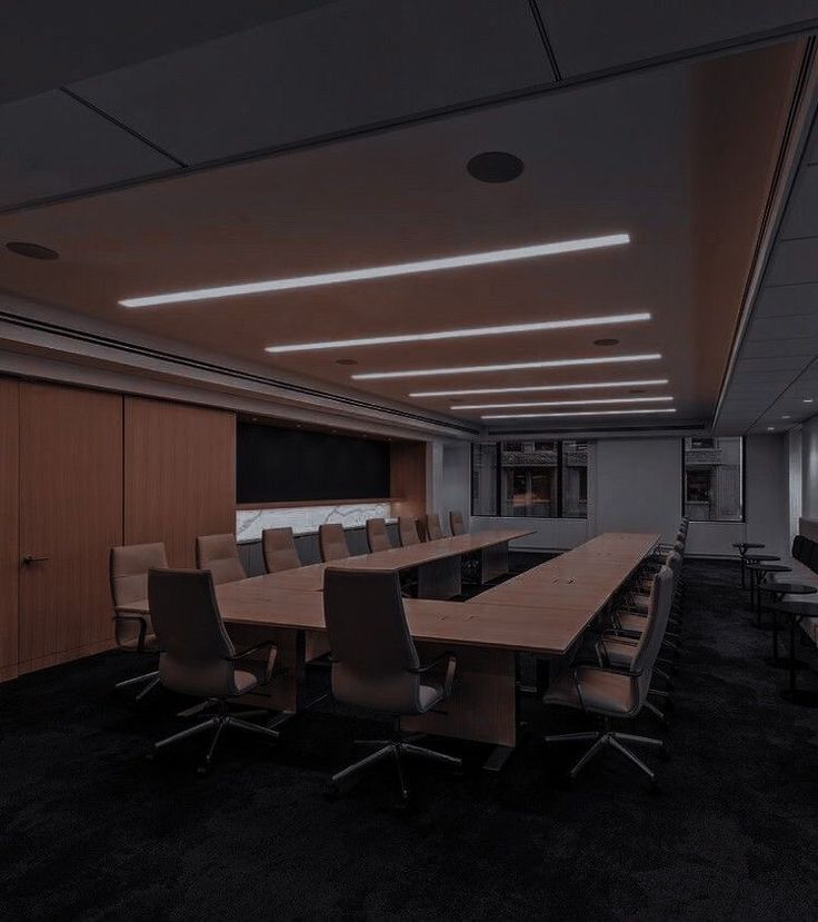 an empty conference room with long tables and chairs in the center, along with black carpeting