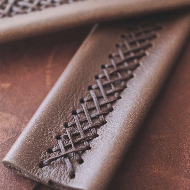 a leather case sitting on top of a table next to a piece of cloth with an intricate design