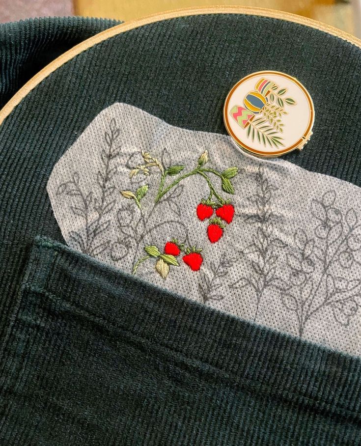 a close up of a piece of cloth with flowers on it and a pin in the pocket