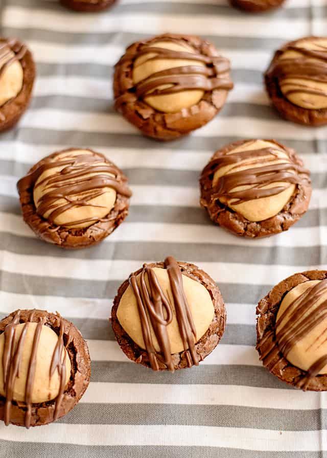 chocolate cookies with peanut butter frosting and drizzled on top, lined up on a striped cloth