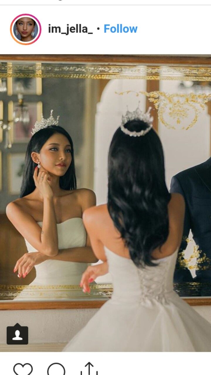 a woman in a wedding dress looking at herself in the mirror with her hand on her face