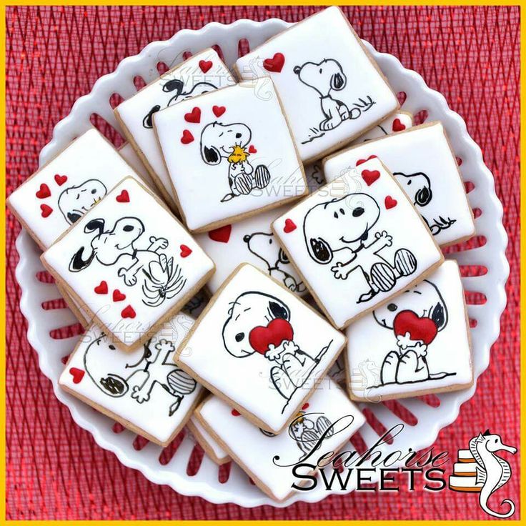 some cookies decorated with pictures of dogs and hearts are sitting on a white platter