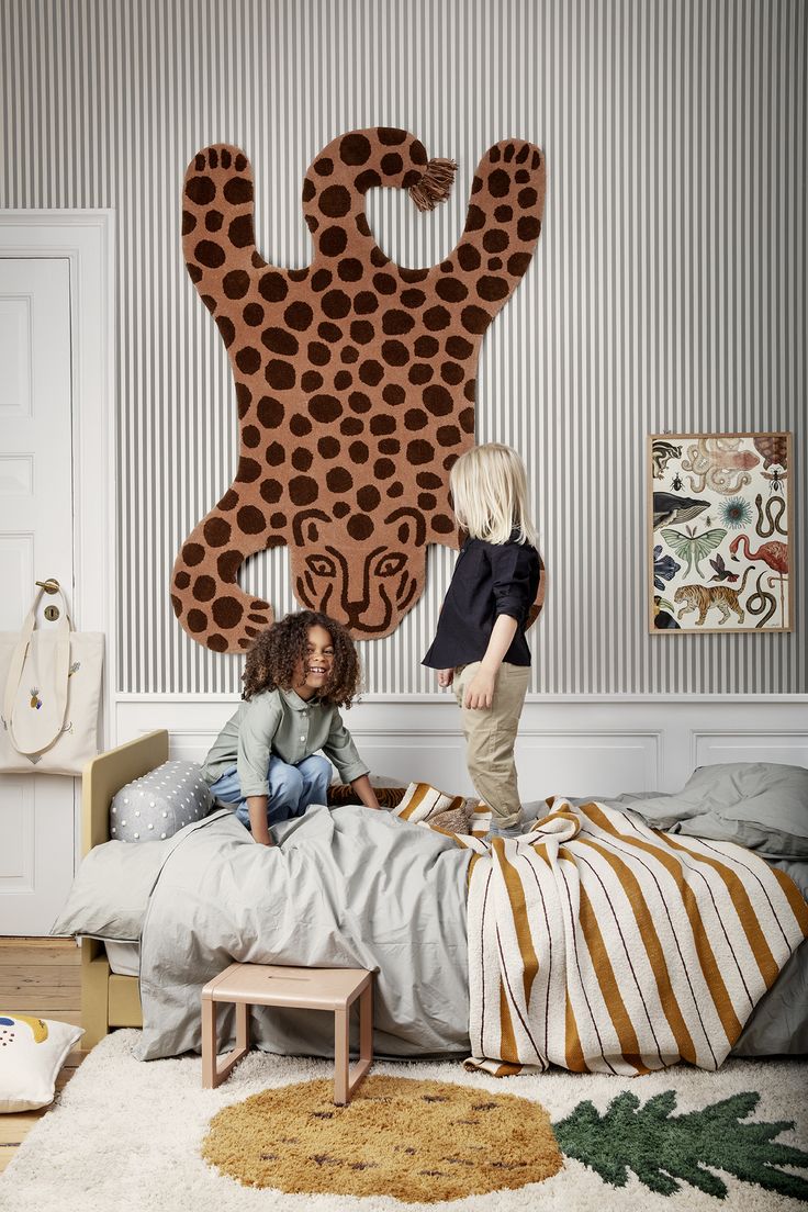 two children are sitting on a bed in front of a large animal head wall hanging