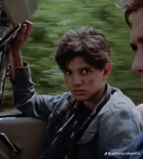 two young boys sitting in the driver's seat of a car looking at each other