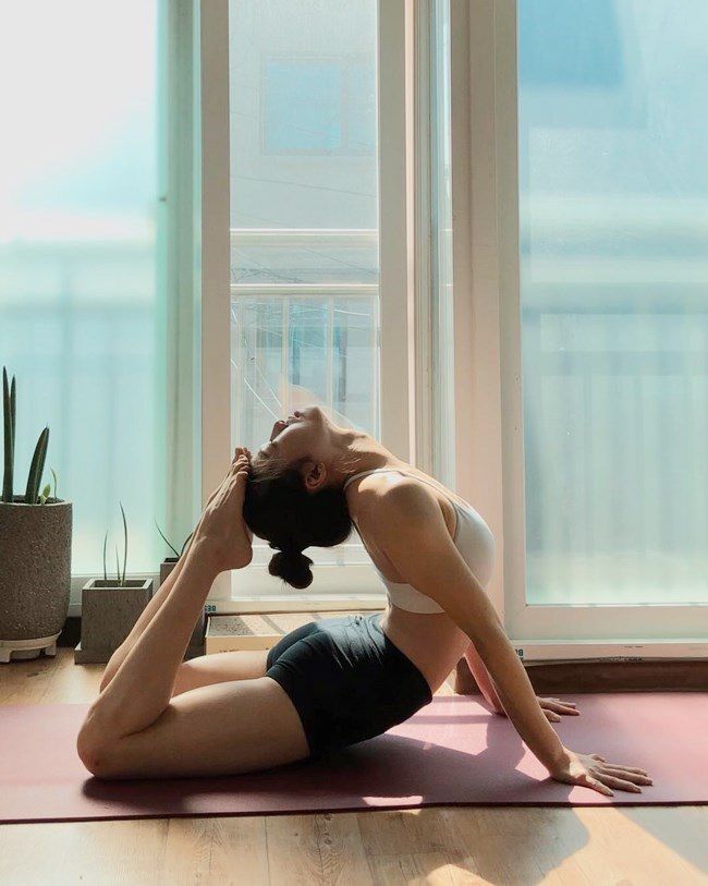 a man is doing yoga in front of a window with his hands behind his head