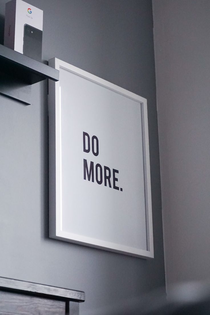 a sign that says do more hanging on the wall next to a shelf in a room