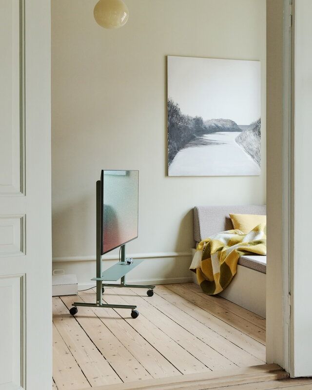 a flat screen tv sitting on top of a wooden floor in a living room next to a window