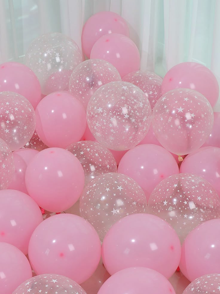 pink and white balloons with glitter on them in a ballon filled room at a birthday party