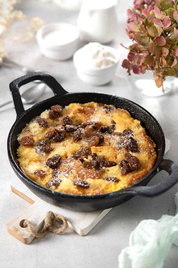 a skillet filled with food sitting on top of a table next to some flowers