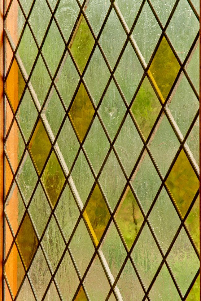 an old stained glass window with green and yellow squares on it's sides,