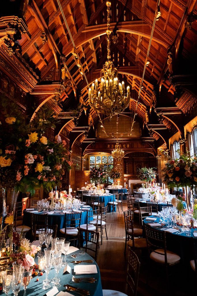 an elaborately decorated dining hall with chandeliers and blue linens on the tables