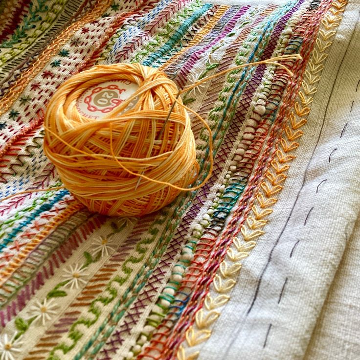 a ball of yarn sitting on top of a colorful blanket