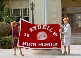 two women holding up a red and white banner that says ryell high school on it