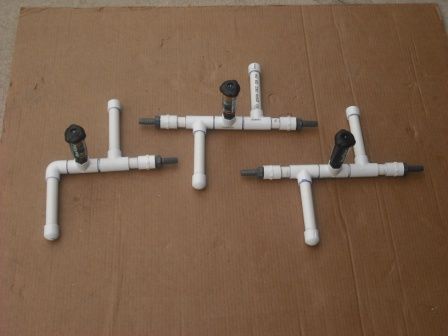 four white pipes connected to each other on top of a brown cardboard box with screws and wrenches