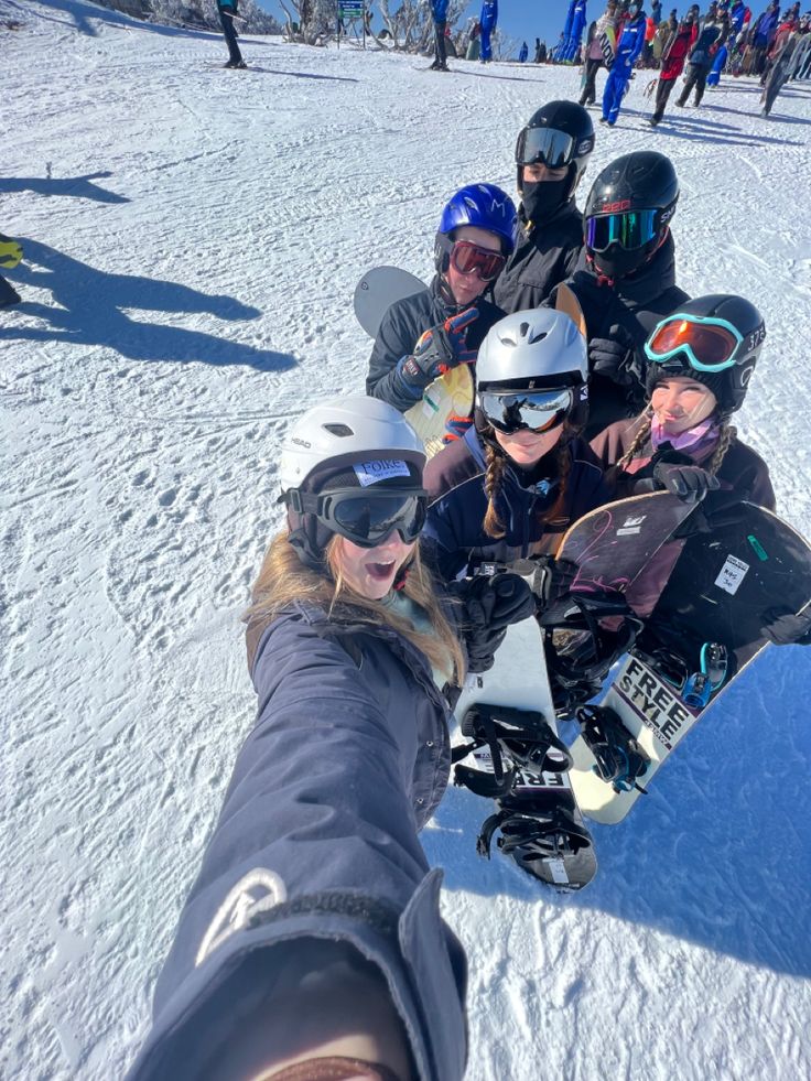 a group of people riding snowboards on top of a snow covered slope with skis