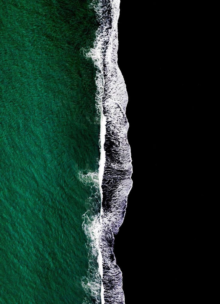 an aerial view of the ocean with waves crashing on it and two surfers in the water