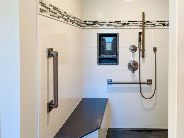 a bathroom with a black counter top and white tiled walls next to a shower head