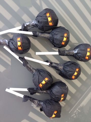 four halloween candles are wrapped in black paper and placed on top of white stick holders