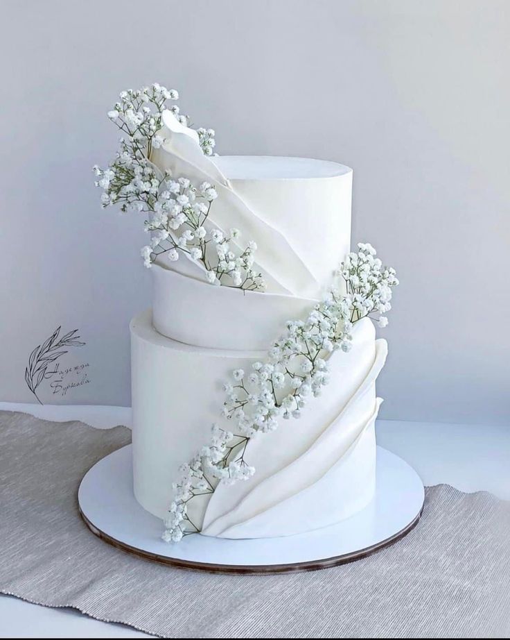 three tiered white wedding cake with flowers on top