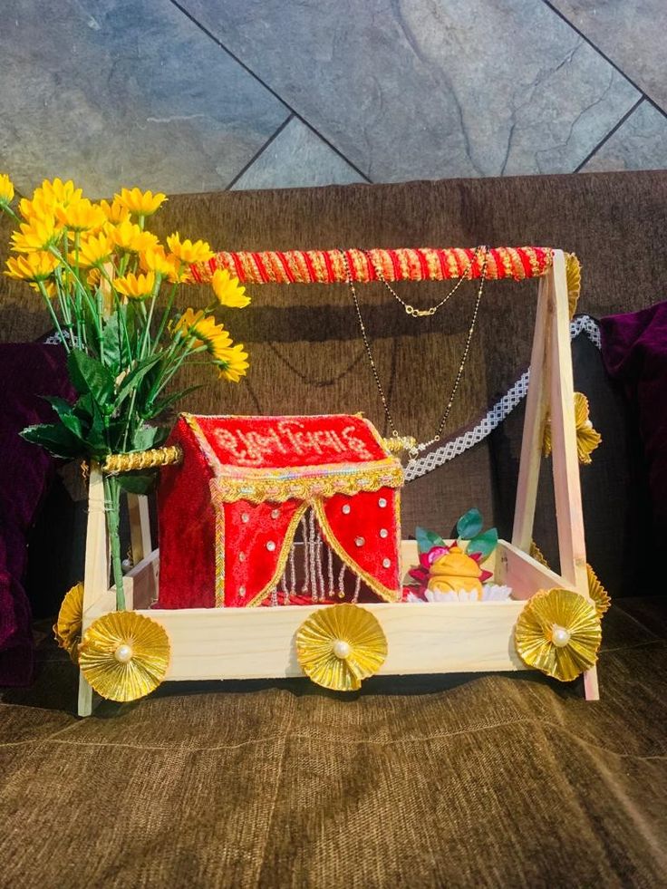 a wooden cart with flowers in it sitting on a couch next to a red and white box