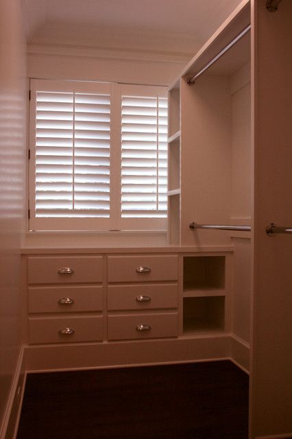 an empty walk in closet with white drawers