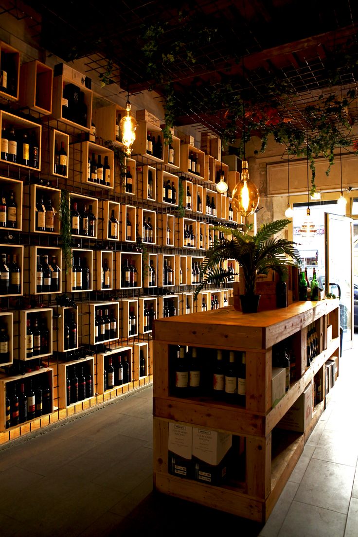 a room filled with lots of bottles of wine next to a wooden shelf covered in plants