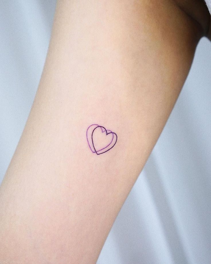 a small heart tattoo on the arm