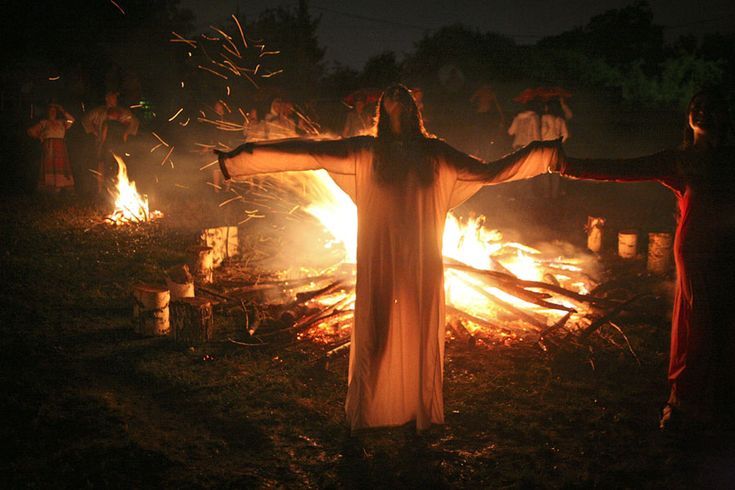 two people standing in front of a fire with their arms spread out and hands outstretched